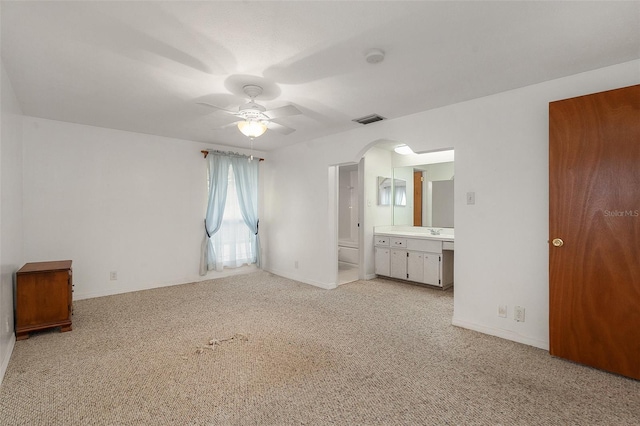 unfurnished bedroom with ceiling fan, light colored carpet, sink, and ensuite bath