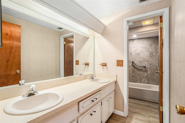 bathroom with vanity, hardwood / wood-style flooring, tiled shower / bath, and a textured ceiling