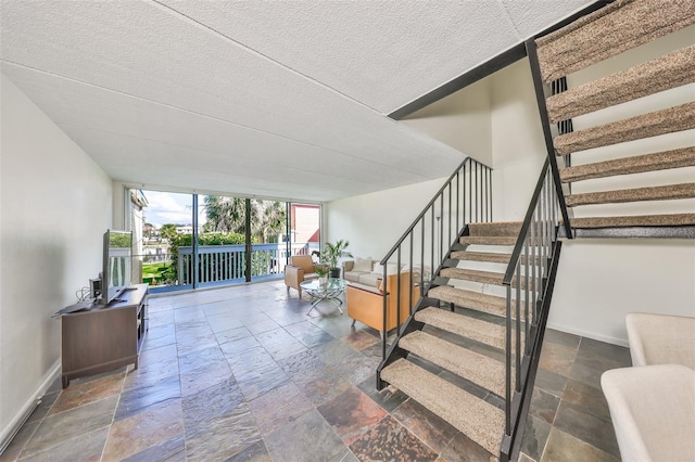 stairway featuring a textured ceiling and a wall of windows