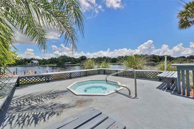 view of pool with a patio area, a water view, and an in ground hot tub