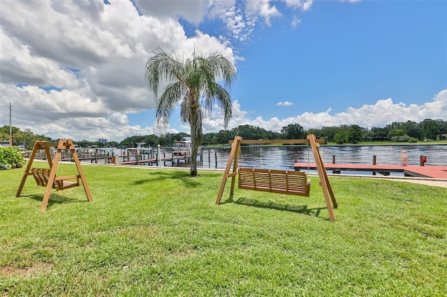 surrounding community with a water view, a dock, and a lawn