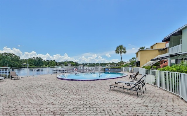 view of pool with a patio area and a water view