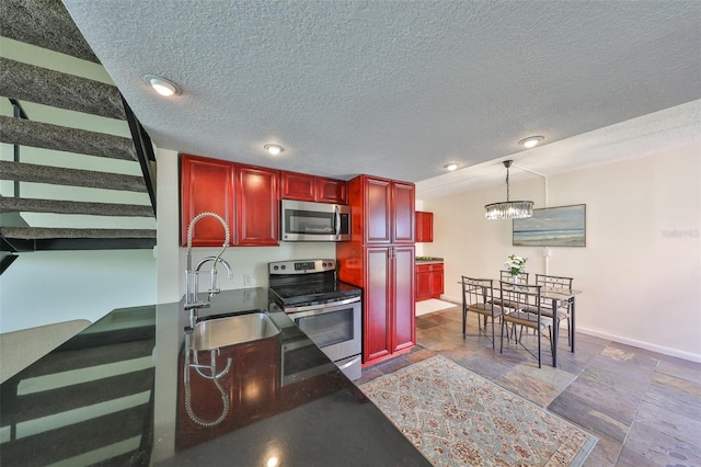 kitchen featuring sink, a chandelier, a textured ceiling, pendant lighting, and stainless steel appliances