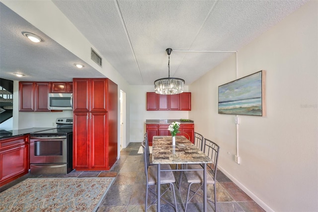 kitchen with stainless steel appliances, decorative light fixtures, a chandelier, and a textured ceiling