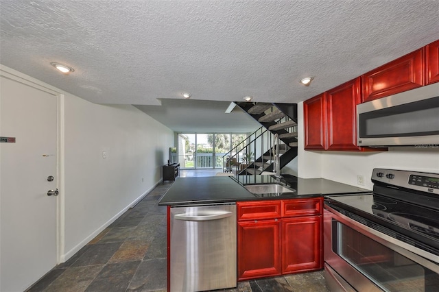 kitchen featuring stainless steel appliances, kitchen peninsula, and a textured ceiling