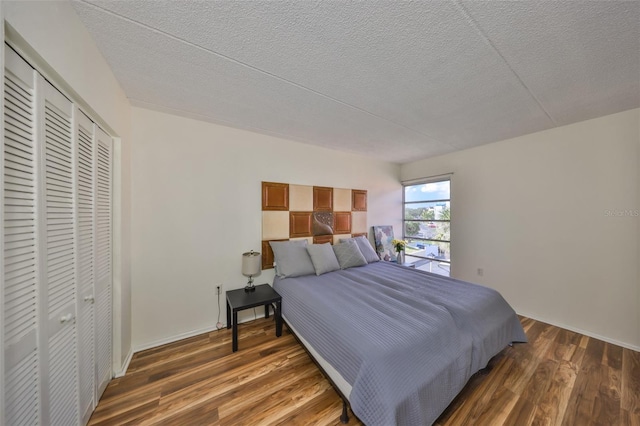 bedroom with dark hardwood / wood-style floors, a textured ceiling, and a closet