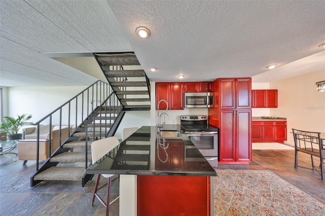 2424 W Tampa Bay Blvd Unit B201, Tampa, FL 33607 - kitchen with appliances with stainless steel finishes, dark brown cabinets, a sink, a textured ceiling, and dark countertops