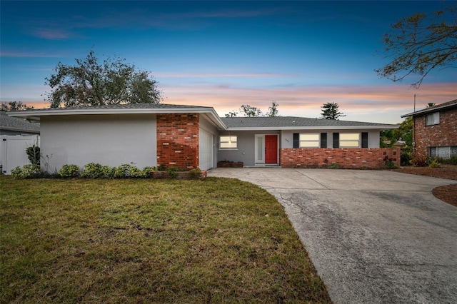 single story home featuring a garage and a lawn