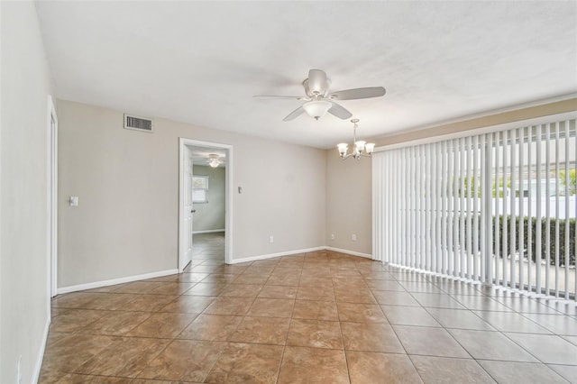 tiled empty room with ceiling fan with notable chandelier