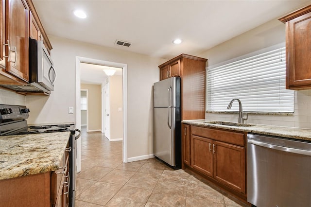 kitchen with tasteful backsplash, sink, light stone counters, and stainless steel appliances