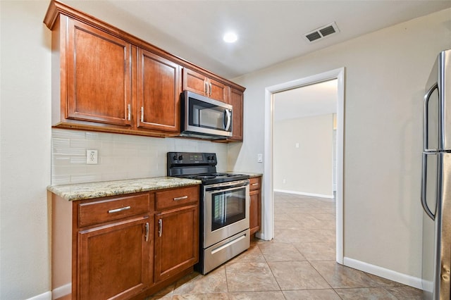 kitchen featuring light stone counters, light tile patterned floors, appliances with stainless steel finishes, and tasteful backsplash