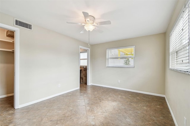 unfurnished bedroom with a spacious closet, a closet, and ceiling fan