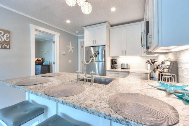 kitchen featuring tasteful backsplash, ornamental molding, white cabinets, stainless steel fridge, and light stone counters