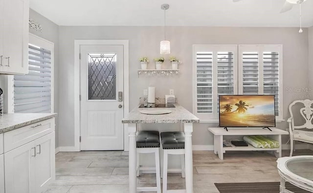 kitchen featuring light stone countertops, white cabinetry, and decorative light fixtures