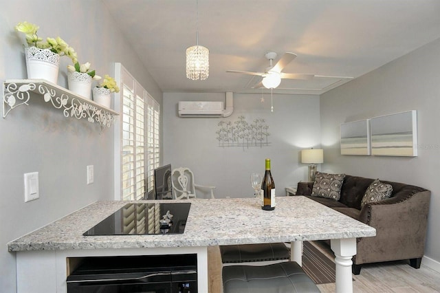 kitchen with an AC wall unit, light stone countertops, oven, ceiling fan, and black electric cooktop