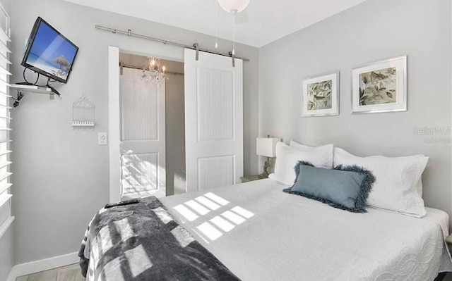 bedroom featuring ceiling fan, a barn door, and hardwood / wood-style floors