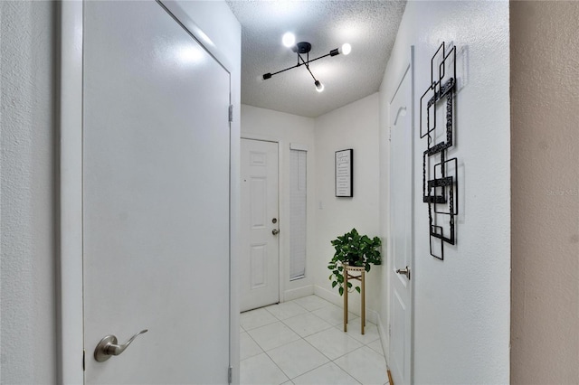 corridor featuring light tile patterned floors and a textured ceiling