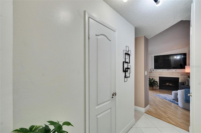 hall featuring a textured ceiling and light tile patterned flooring