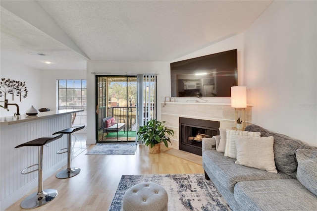 living room featuring hardwood / wood-style flooring, vaulted ceiling, and a textured ceiling