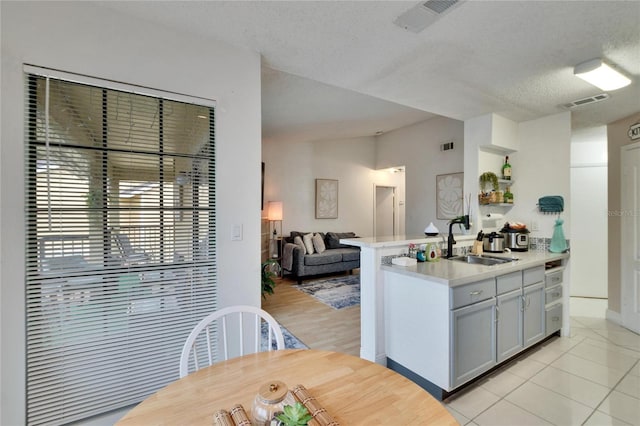 kitchen featuring sink, light tile patterned floors, kitchen peninsula, and a textured ceiling