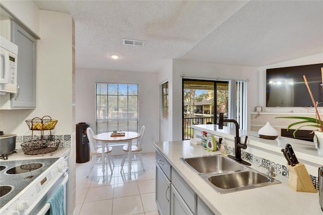 kitchen featuring sink, gray cabinetry, a textured ceiling, light tile patterned floors, and a healthy amount of sunlight