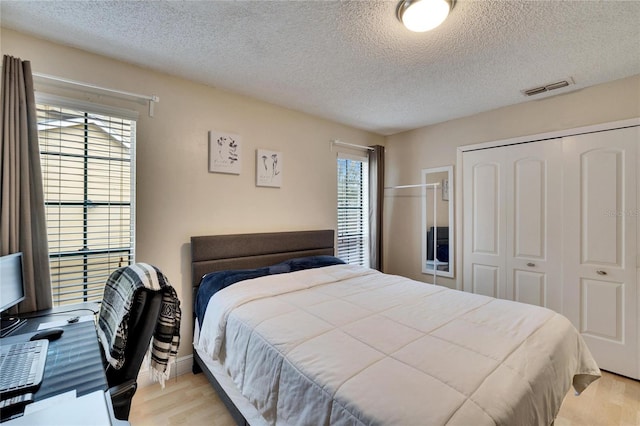 bedroom featuring light wood-type flooring, a textured ceiling, and a closet