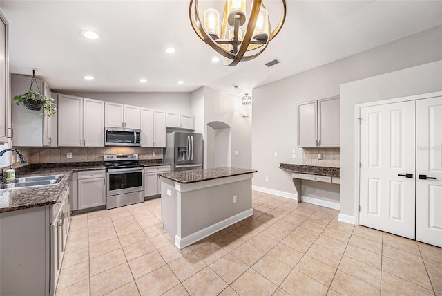 kitchen featuring sink, a center island, vaulted ceiling, appliances with stainless steel finishes, and backsplash