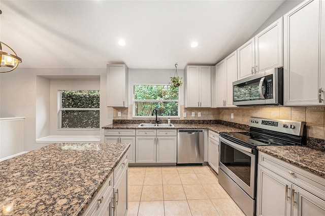 kitchen with white cabinetry, appliances with stainless steel finishes, sink, and dark stone counters