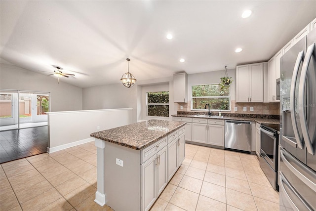 kitchen with light tile patterned flooring, stainless steel appliances, decorative light fixtures, and a kitchen island