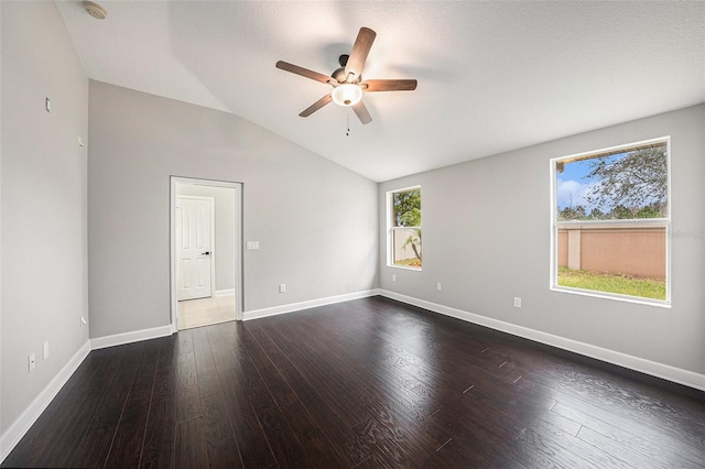 empty room with lofted ceiling, plenty of natural light, dark wood-type flooring, and ceiling fan