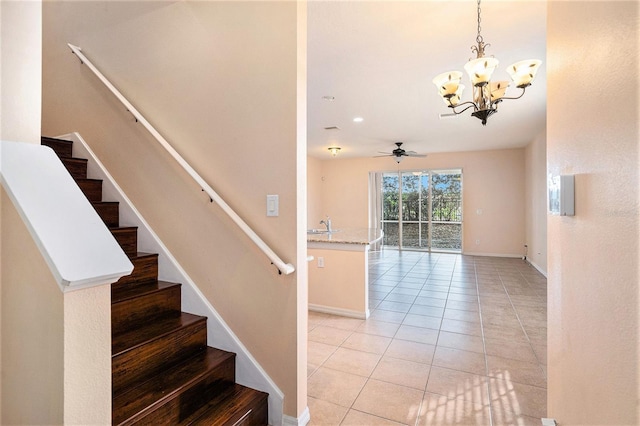 staircase with tile patterned flooring, sink, and ceiling fan with notable chandelier