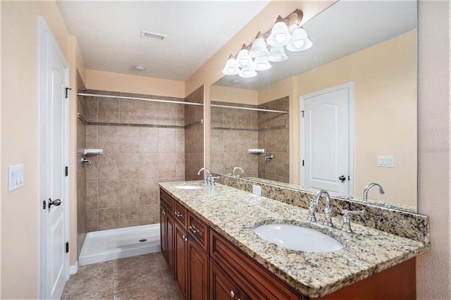 bathroom with vanity, tile patterned flooring, and tiled shower