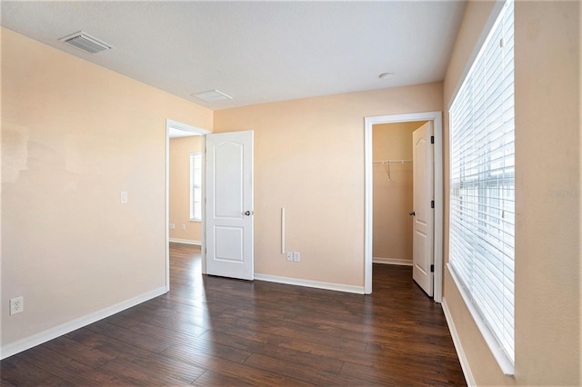 unfurnished bedroom with dark hardwood / wood-style flooring, a closet, and a spacious closet