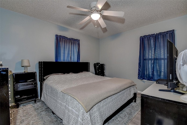 bedroom with ceiling fan, hardwood / wood-style floors, and a textured ceiling