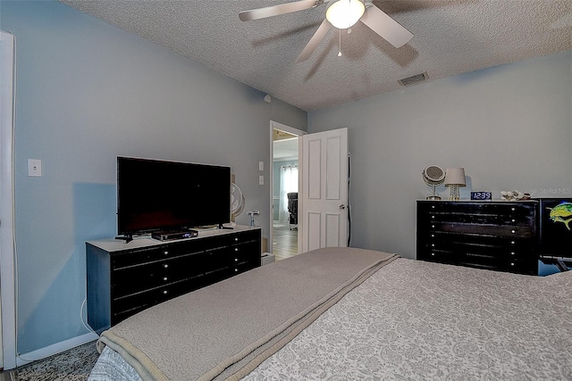 bedroom with ceiling fan and a textured ceiling