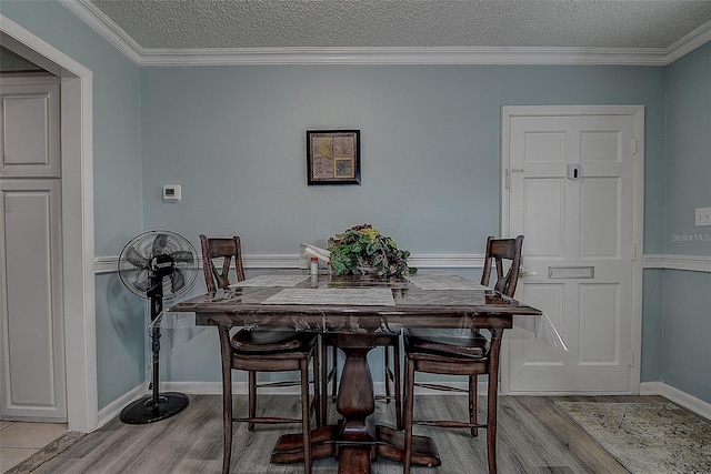 dining space featuring crown molding, a textured ceiling, and light hardwood / wood-style flooring