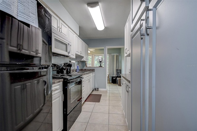 kitchen featuring sink, light tile patterned flooring, black appliances, and white cabinets