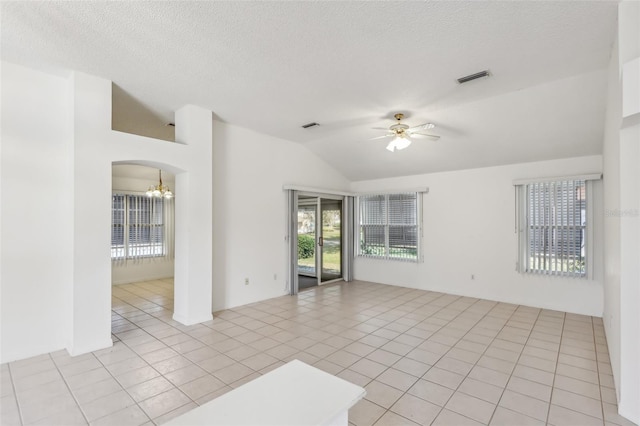 tiled spare room with vaulted ceiling, ceiling fan with notable chandelier, and a textured ceiling