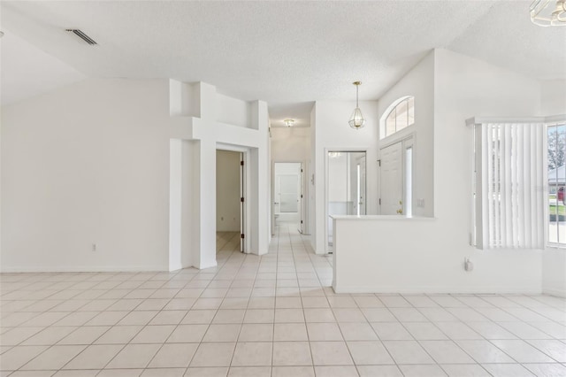 unfurnished room featuring lofted ceiling, light tile patterned floors, and a textured ceiling