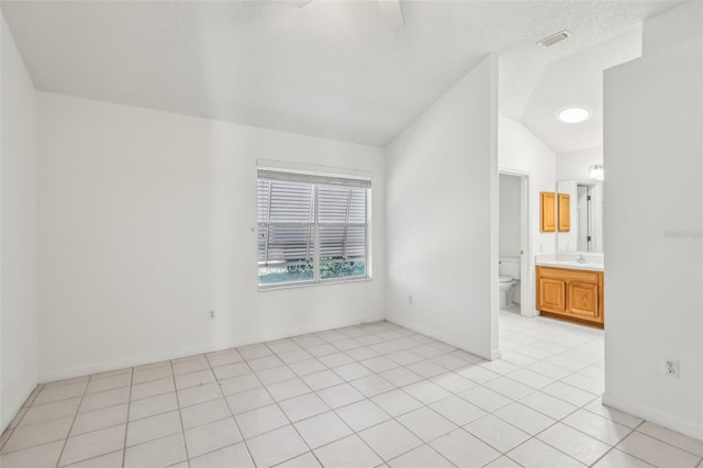 empty room featuring lofted ceiling, sink, and light tile patterned floors