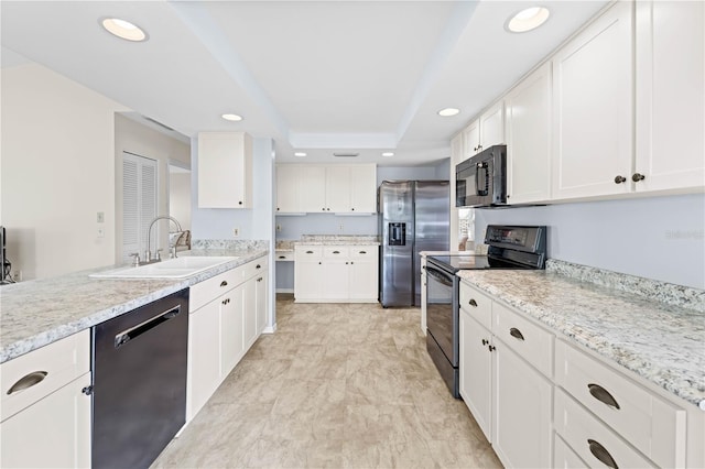 kitchen featuring a raised ceiling, white cabinetry, sink, and black appliances