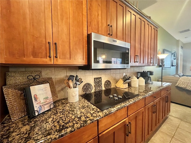 kitchen with black electric stovetop, dark stone counters, and decorative backsplash