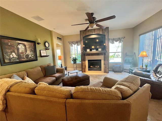 carpeted living room with ceiling fan and a fireplace