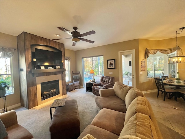 living room with a fireplace, ceiling fan with notable chandelier, and light carpet