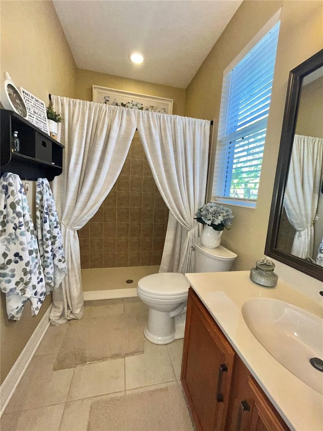 bathroom featuring a tile shower, vanity, tile patterned flooring, and toilet