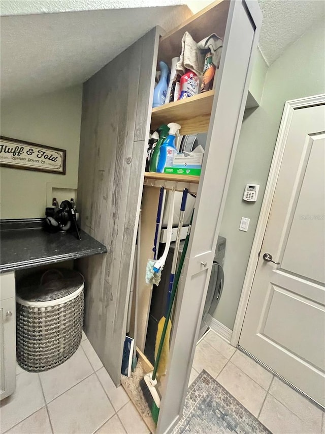 laundry area featuring a textured ceiling and light tile patterned floors