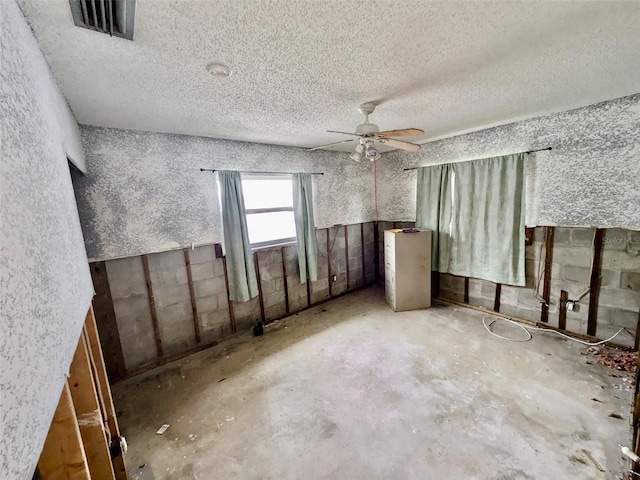 empty room featuring a textured ceiling, ceiling fan, and concrete flooring