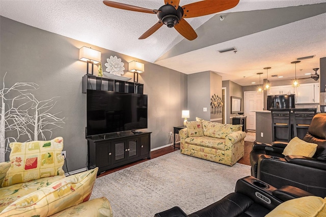 living room featuring a textured ceiling, vaulted ceiling, and ceiling fan