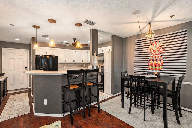 dining area featuring ceiling fan, a textured ceiling, and dark hardwood / wood-style floors