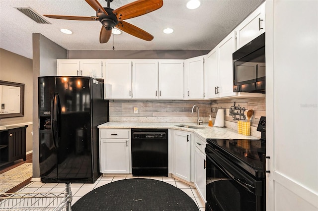 kitchen featuring a textured ceiling, white cabinets, black appliances, sink, and light tile patterned floors